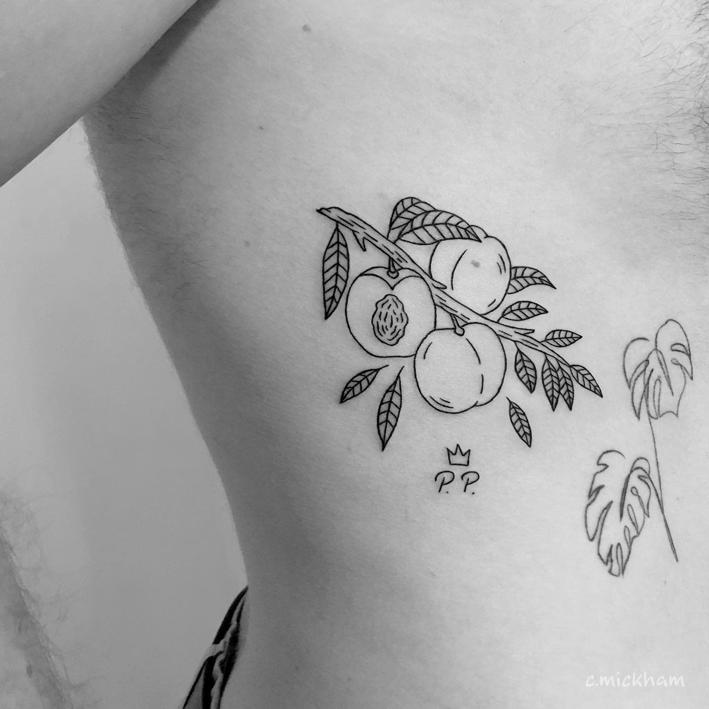Black and white tattoo of peaches on a branch with leaves